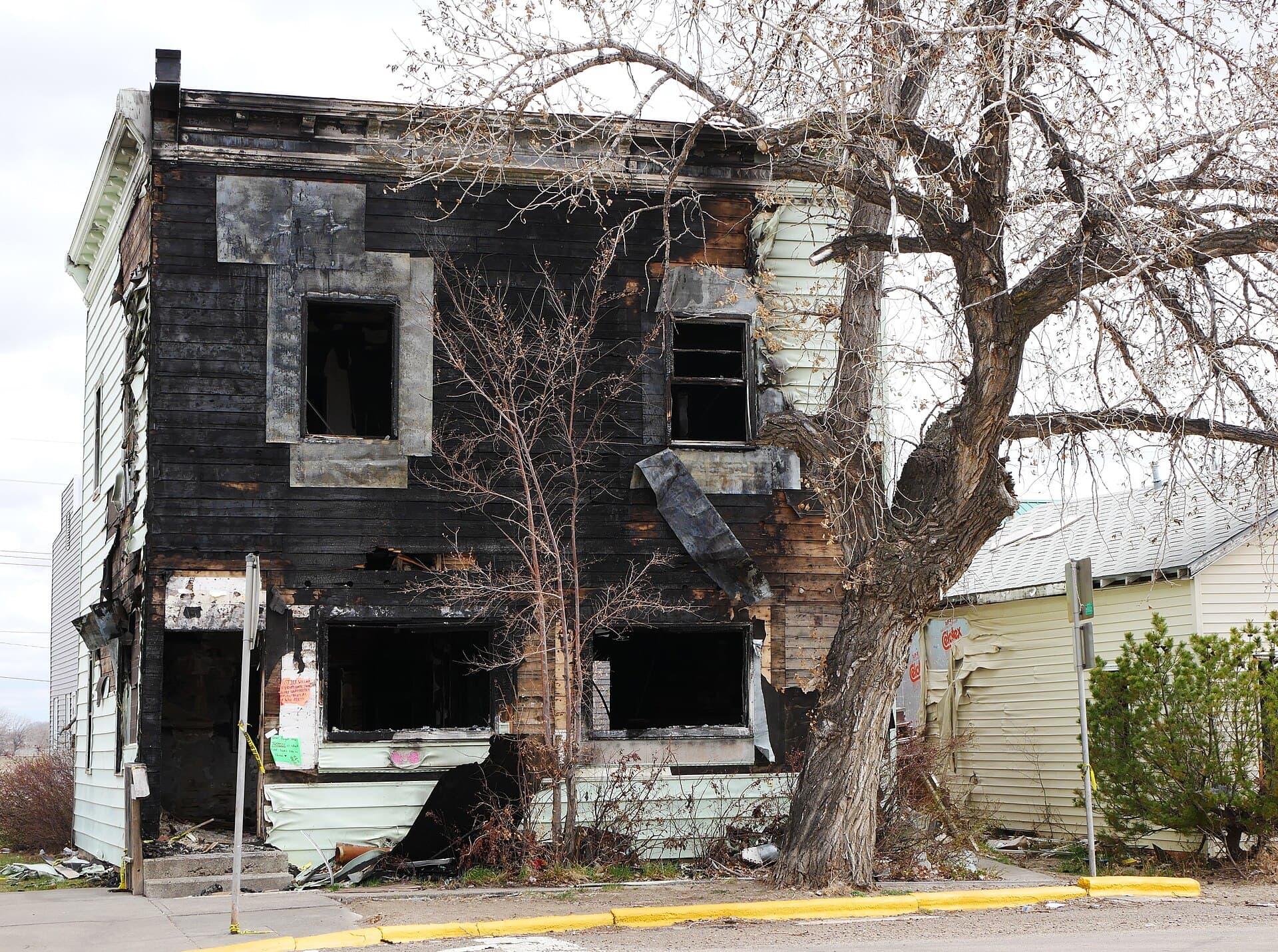 A burned-down house in Wolf Point, Montana, with fire-damaged debris and structure remains.